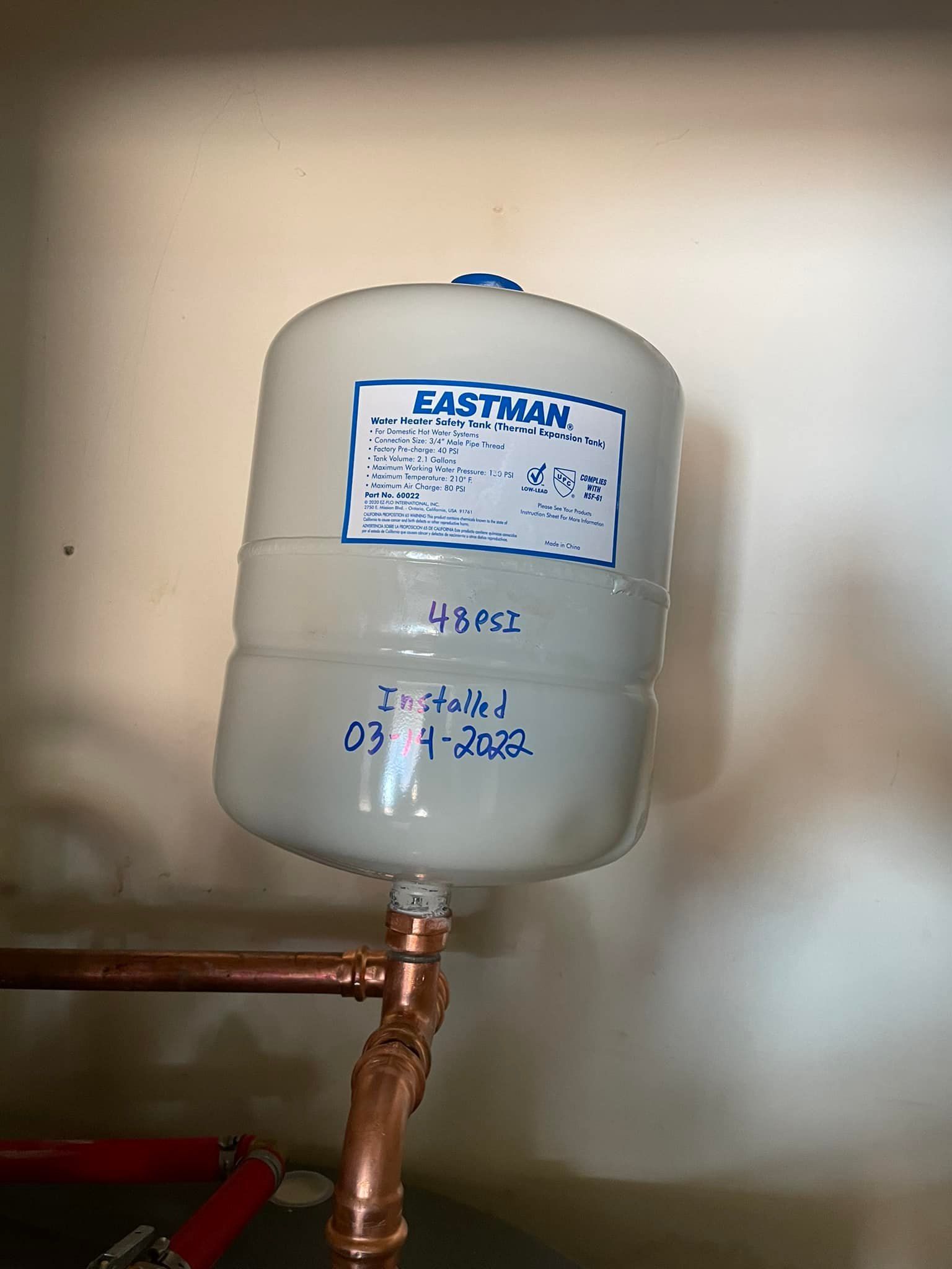 A white tank is sitting on top of a copper pipe.