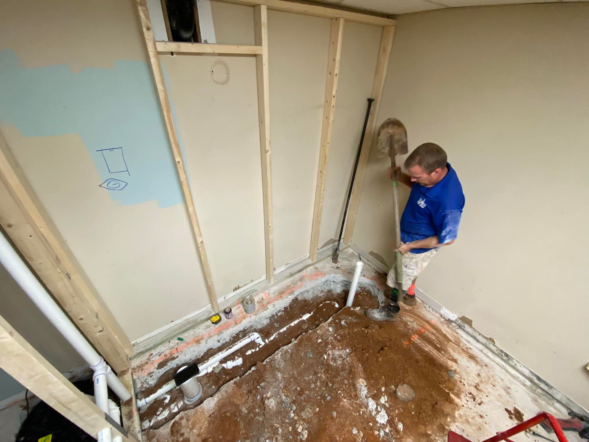 A man is digging a hole in a room with a shovel.