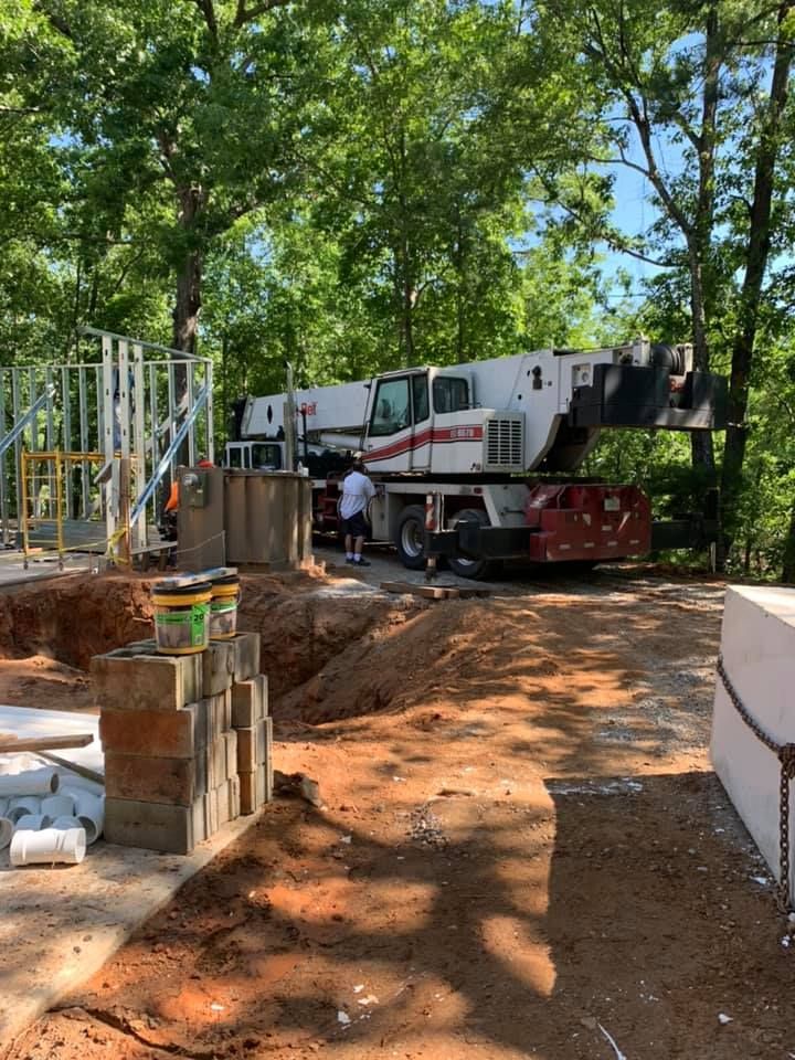 A construction site with a crane and a man standing in the dirt.