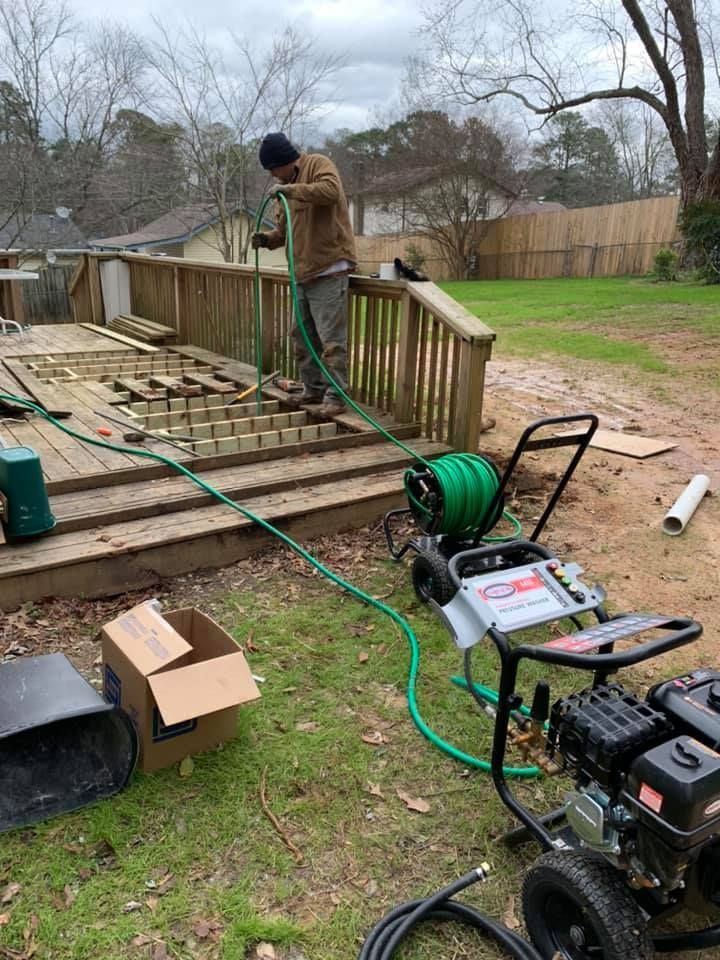 A man is using a hose to clean a deck.