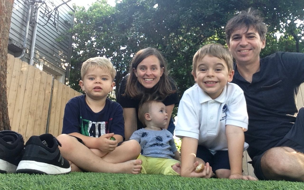 A family is posing for a picture while sitting on the grass.