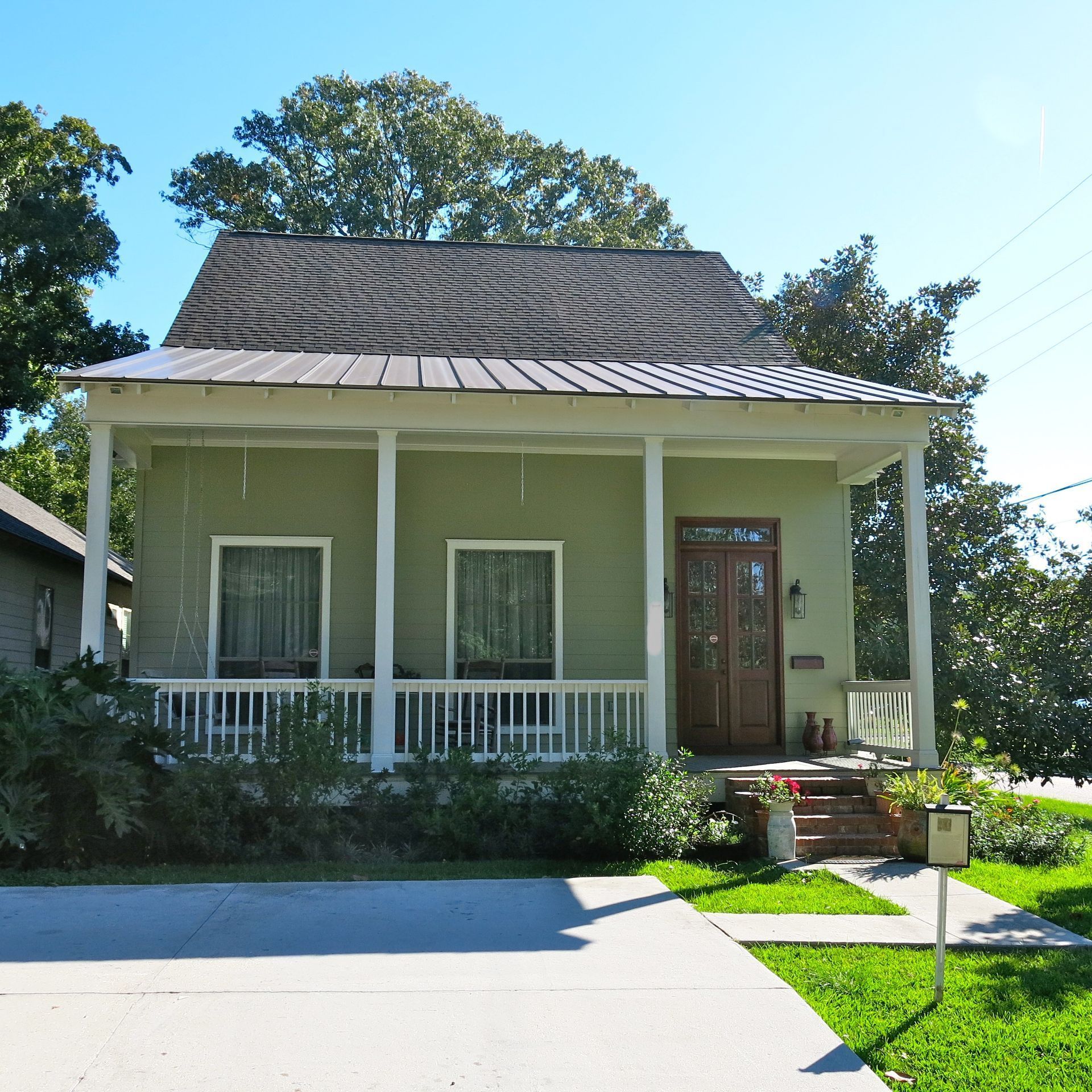 A small green house with a porch and stairs