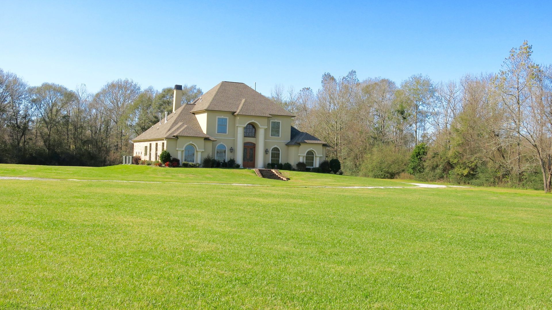 A large house is sitting in the middle of a lush green field.