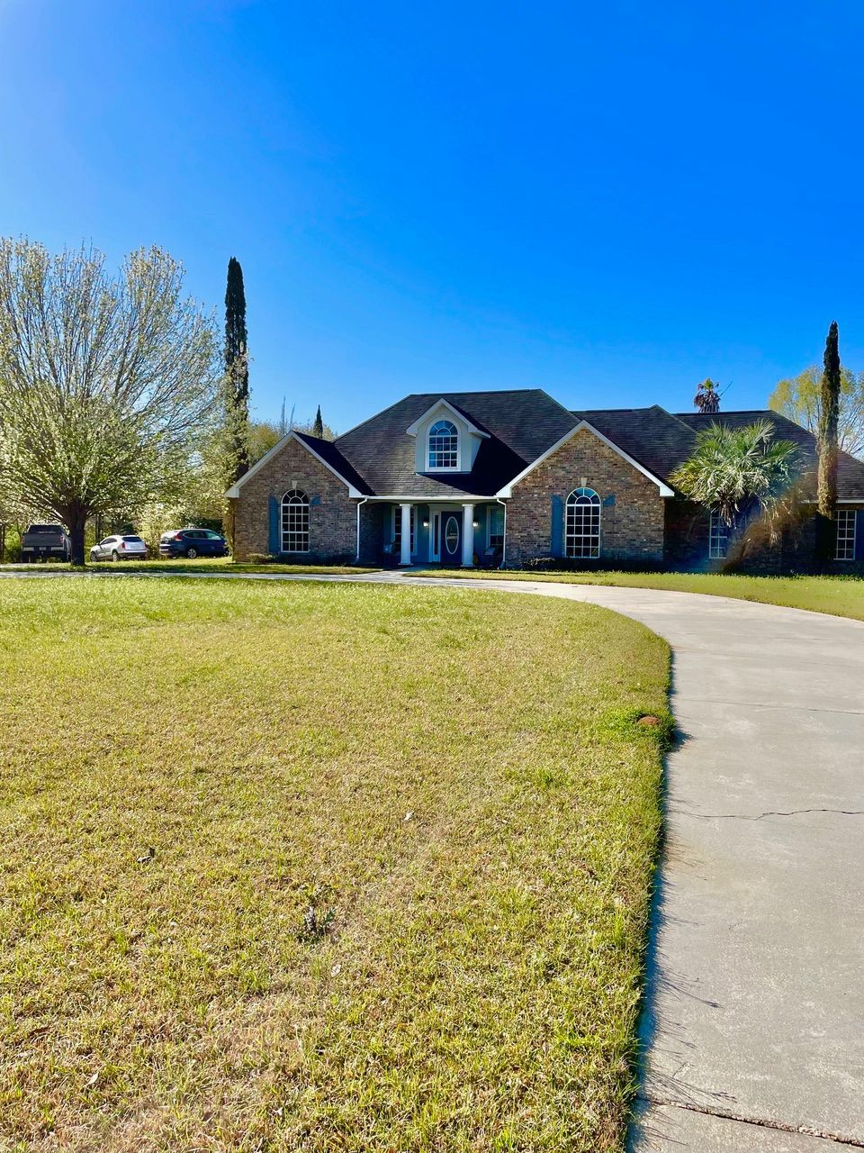A large brick house is sitting on top of a lush green field.