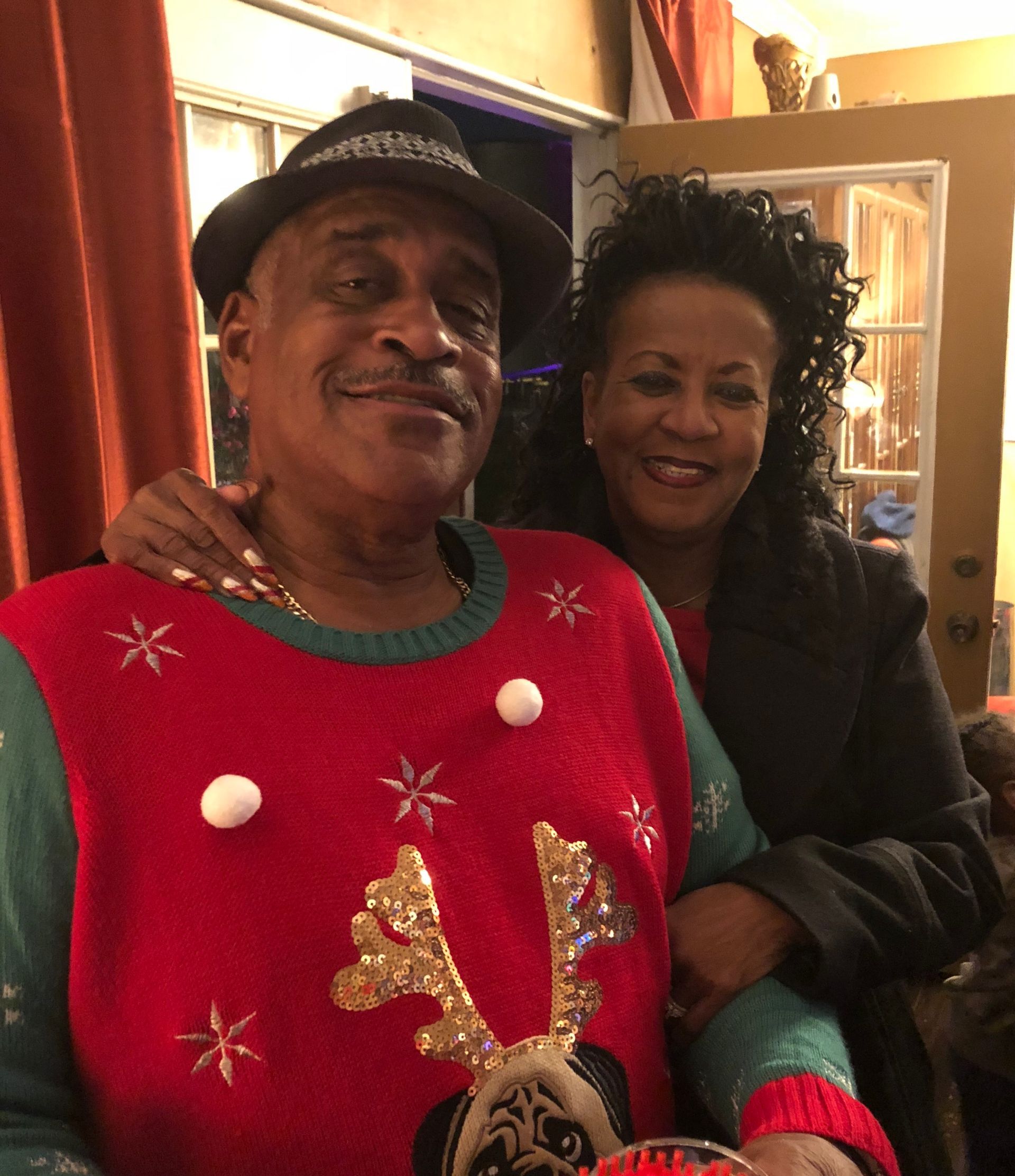 A man wearing a red sweater and a hat is standing next to a woman