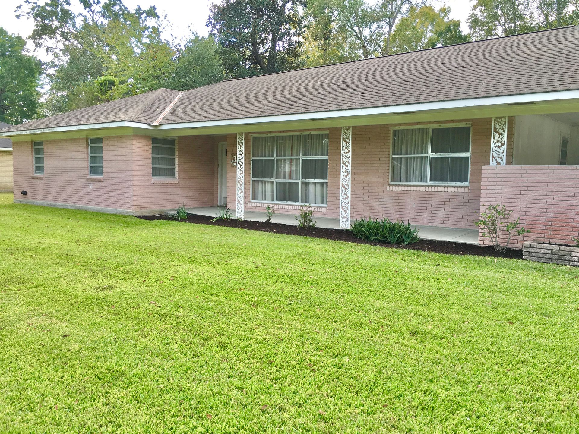 A brick house with a large lawn in front of it.