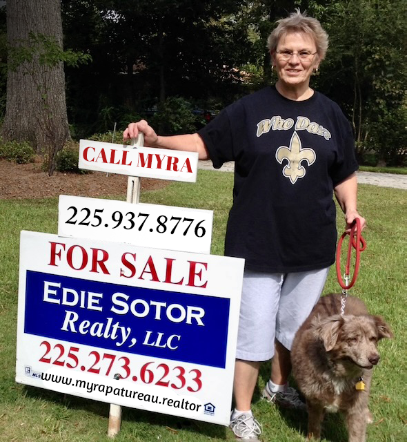 A woman standing next to a for sale sign