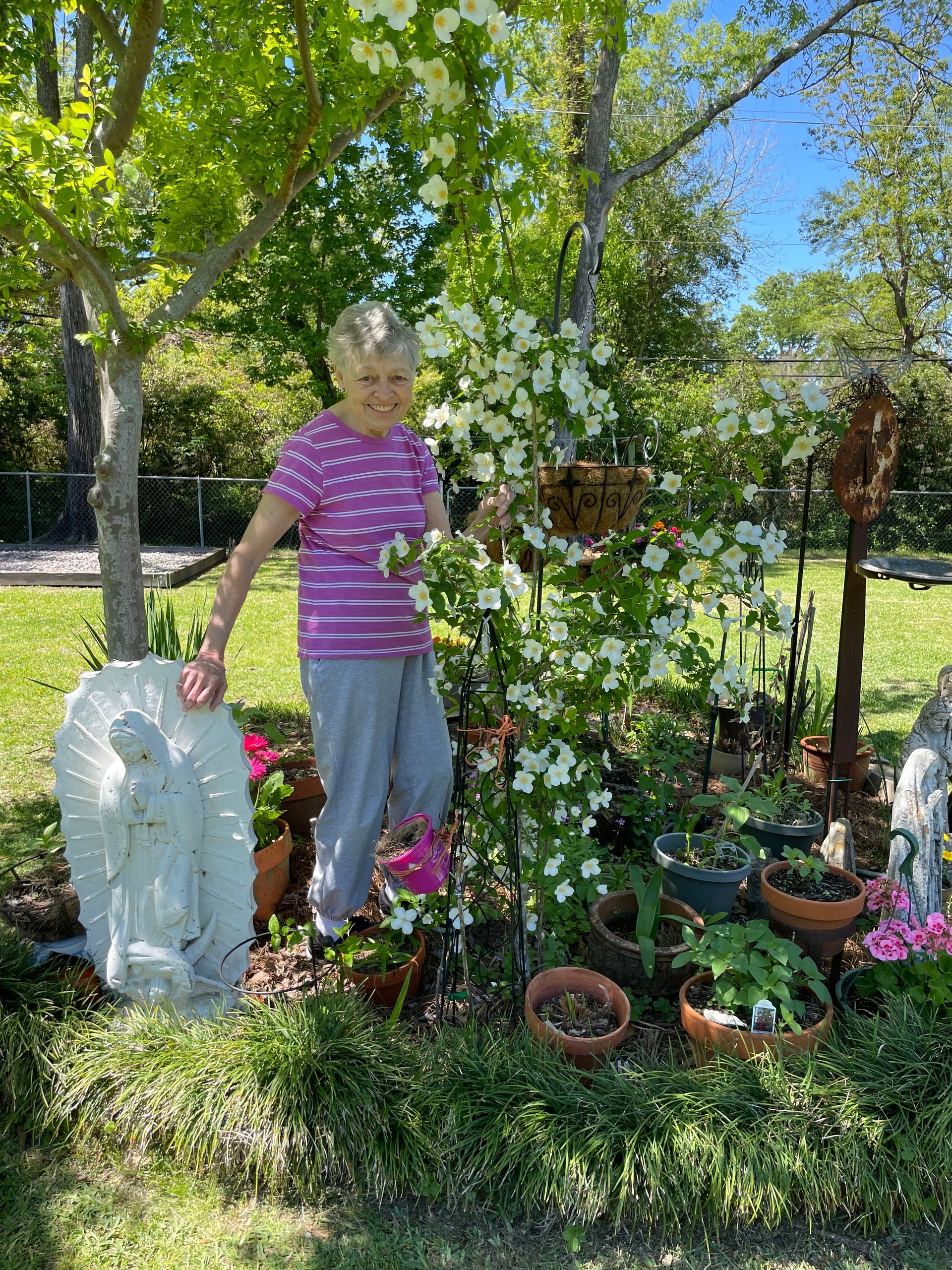 A woman is standing next to a tree in a garden.