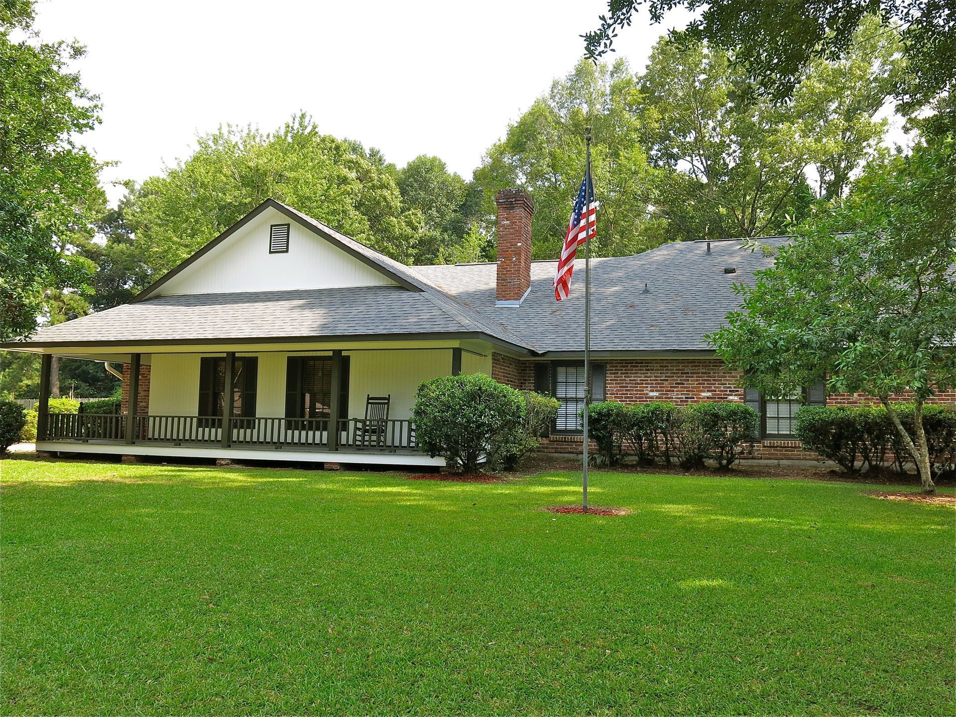 A house with a porch and an american flag in front of it