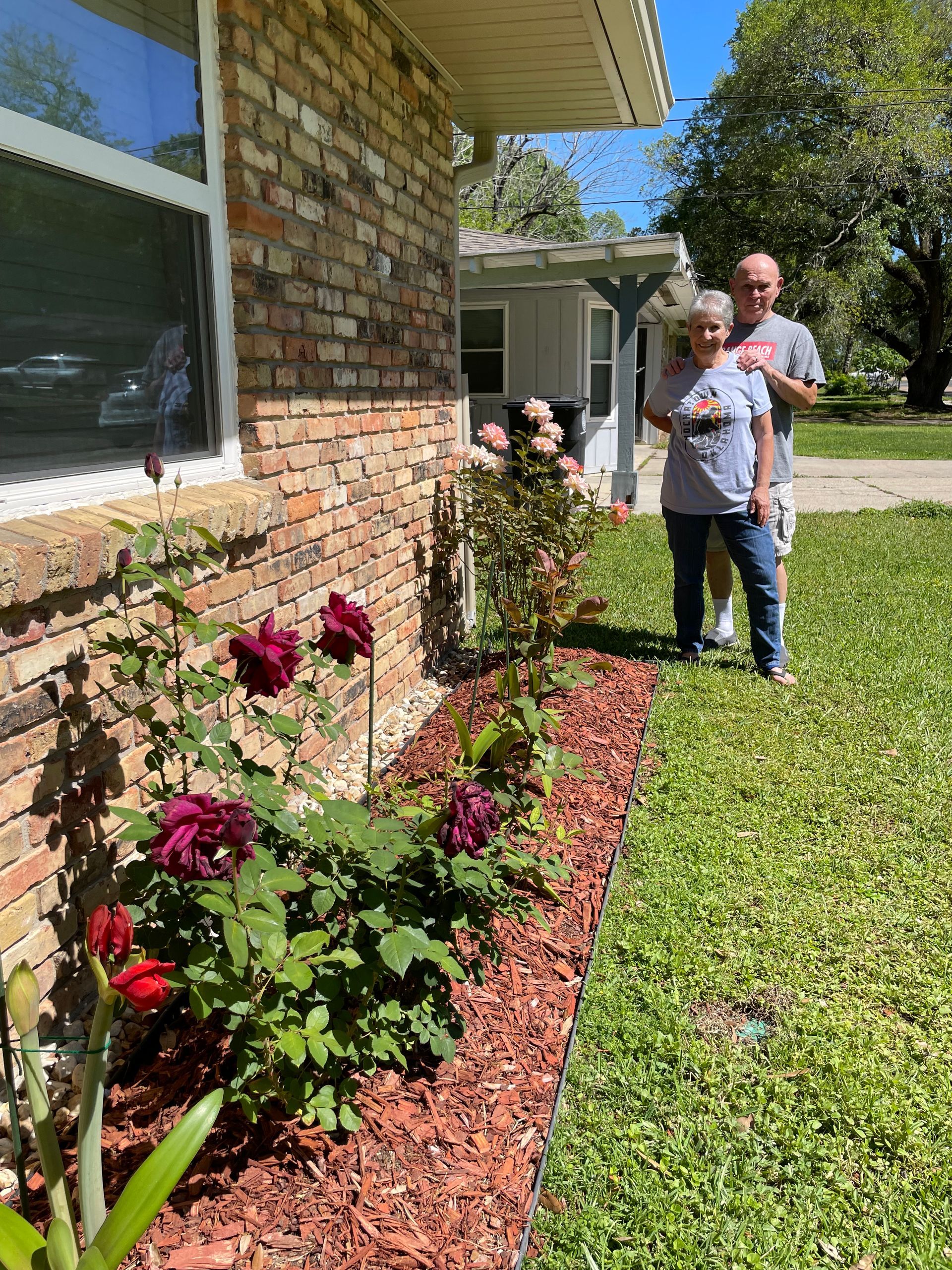 A man and a woman are standing in front of a brick house.