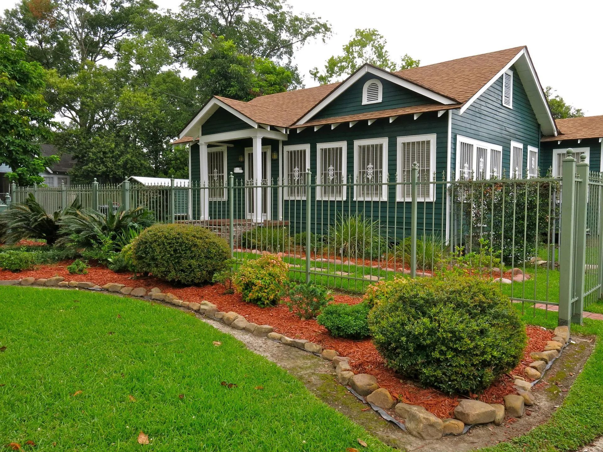 A green house with a fence around it and a lush green yard