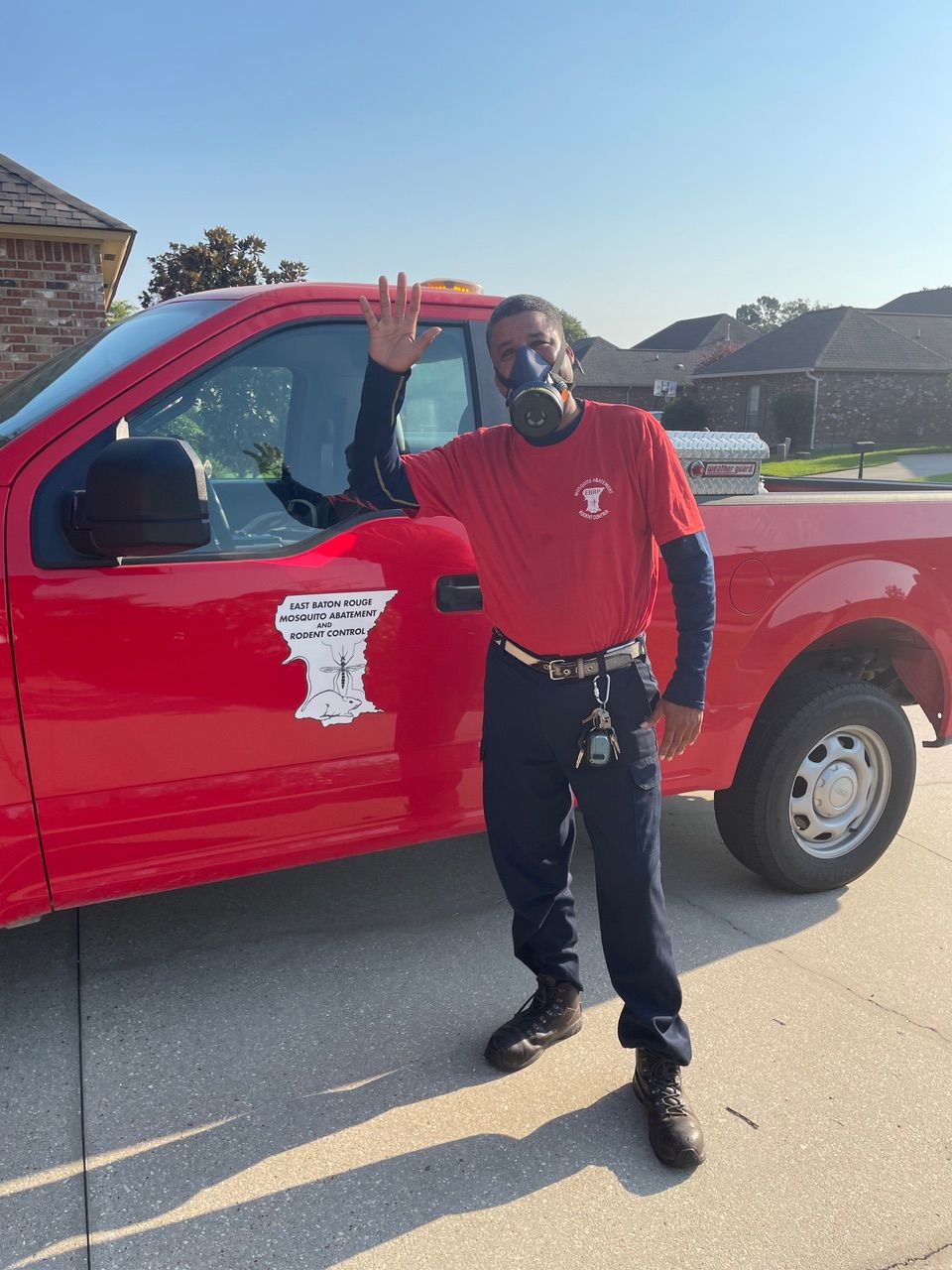 A man wearing a mask is standing in front of a red truck.