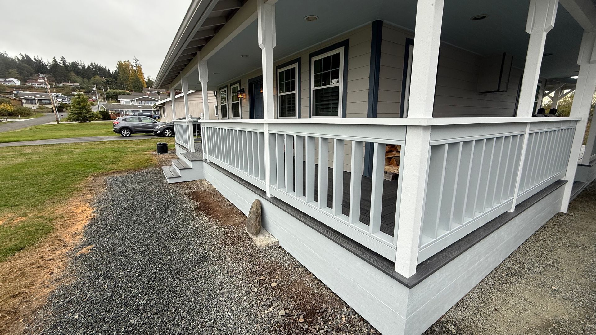 White porch with railings and gravel walkway beside a house on an overcast day