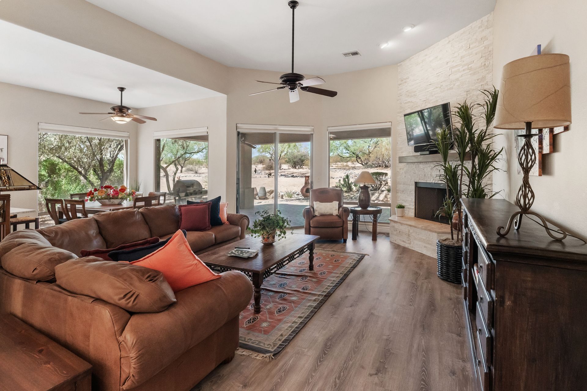 Spacious living room with brown leather sofa, fireplace, and outdoor view through large windows.