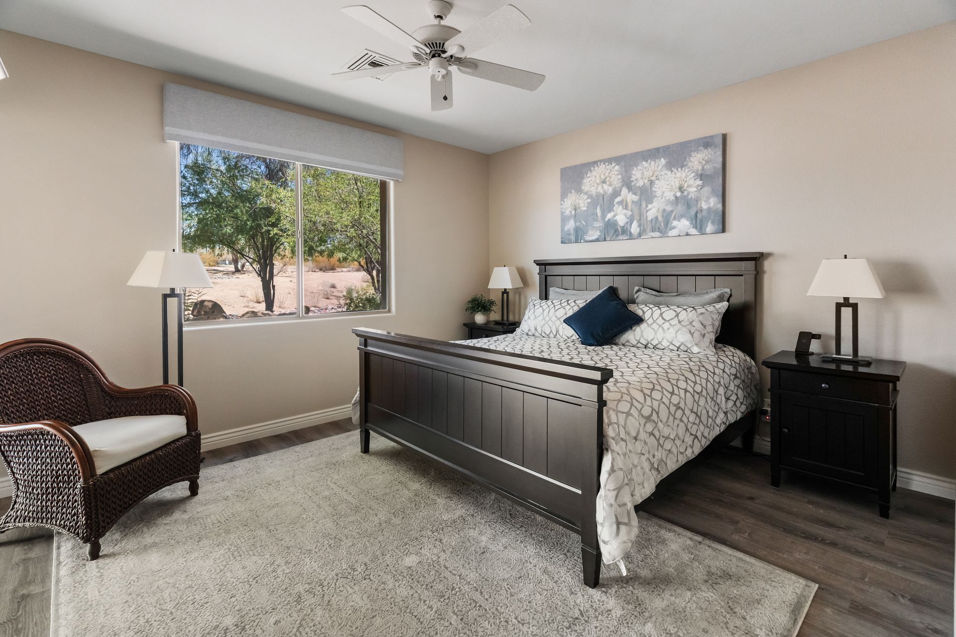 Bedroom with striped red walls, dark wood bed, beige carpet, and a view of a tree-filled outdoor area.
