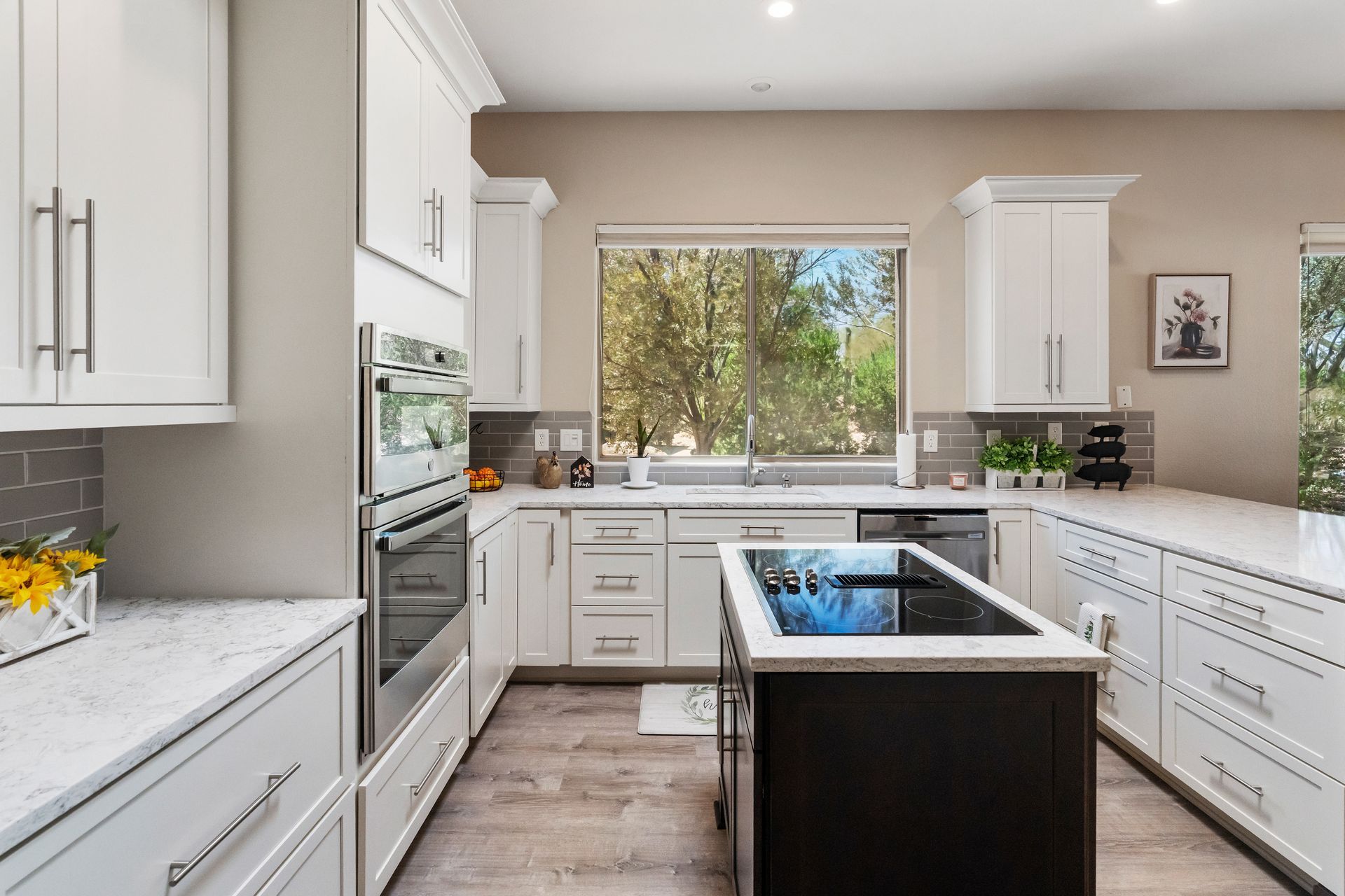 White kitchen with island, cabinets, appliances, and a window.