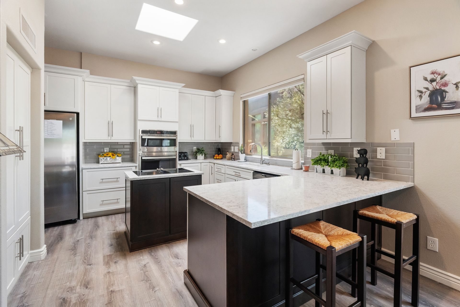 Modern kitchen with white cabinets, dark island, and light countertops.
