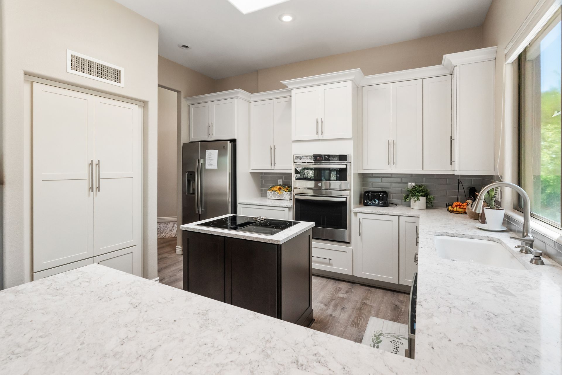 White kitchen with dark island and stainless steel appliances.