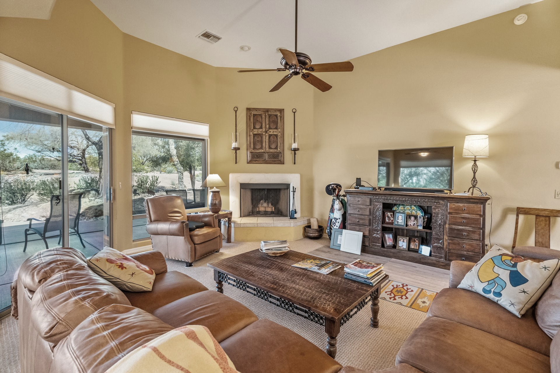 Spacious living room with brown leather furniture, fireplace, and sliding glass doors leading to patio.