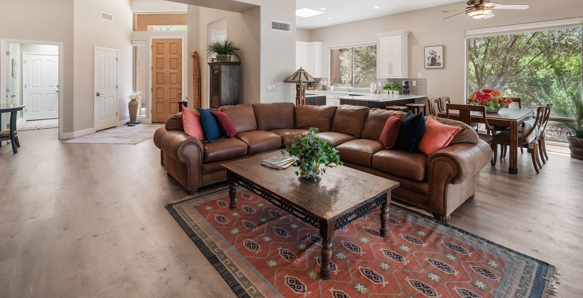 Spacious living room with leather sectional, coffee table, and dining area, hardwood floors.