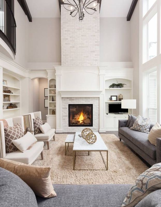 Cozy living room with leather recliner, fireplace, and large window. Tan walls, wood floor, and rug.