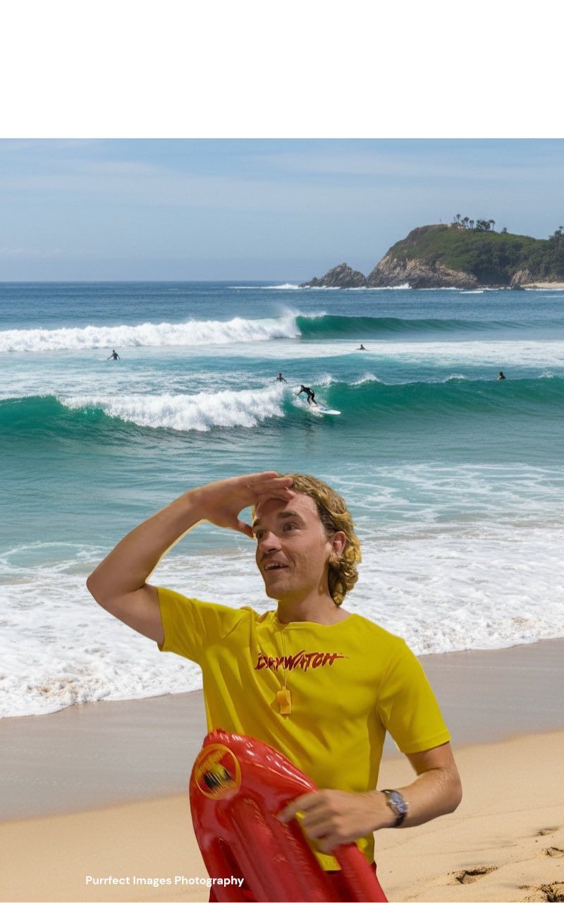Lifeguard on beach looking toward ocean, holding rescue buoy, sunny day — Costumes Galore In Maroochydore, QLD