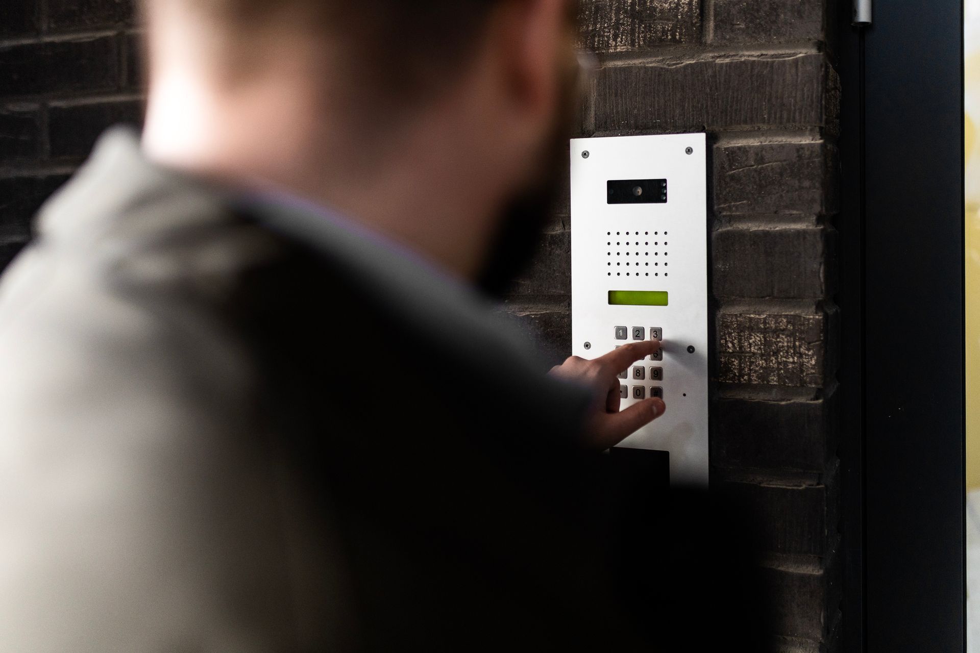 Individual activating an intercom, highlighting functionality in access control systems. Individual activating an intercom, highlighting functionality in access control systems.