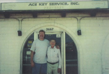 Two people stand smiling in front of the arched entrance of Ace Key Service, Inc. at 3667.