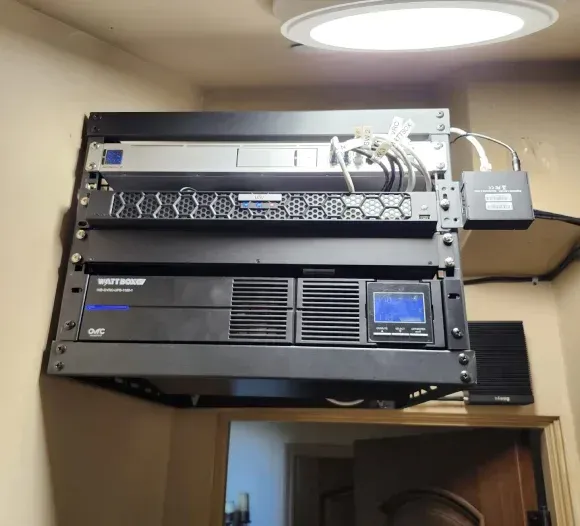 A stack of black boxes on a wall with a light above them