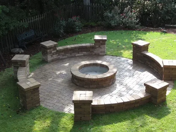 A fire pit in the middle of a lush green yard