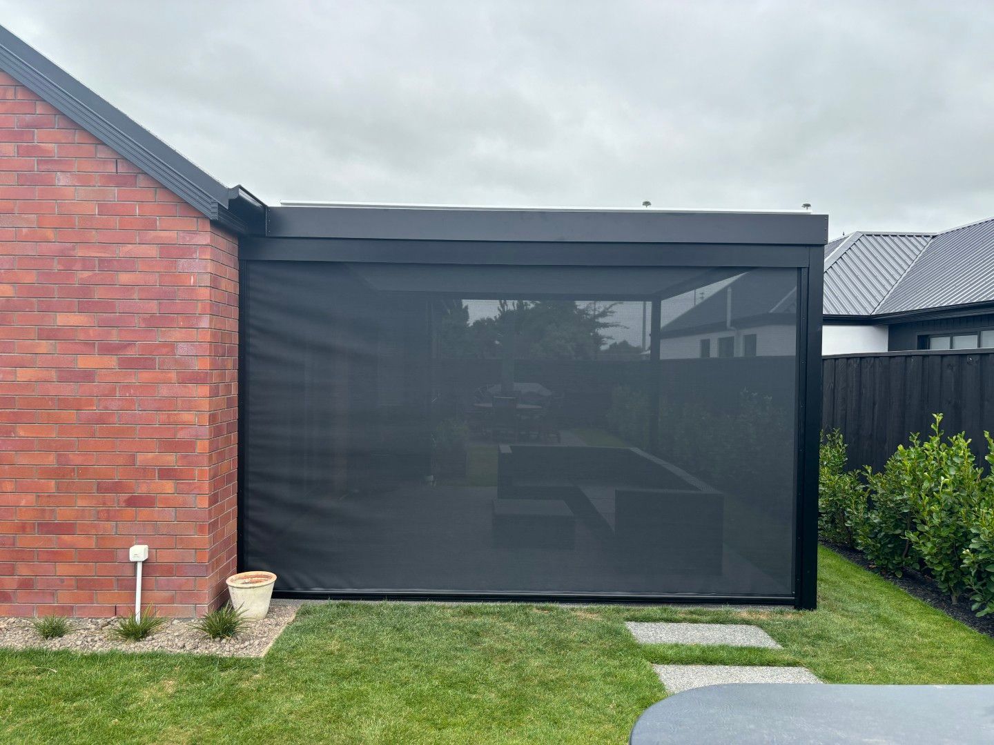 A brick house with a black screen on the side of it.