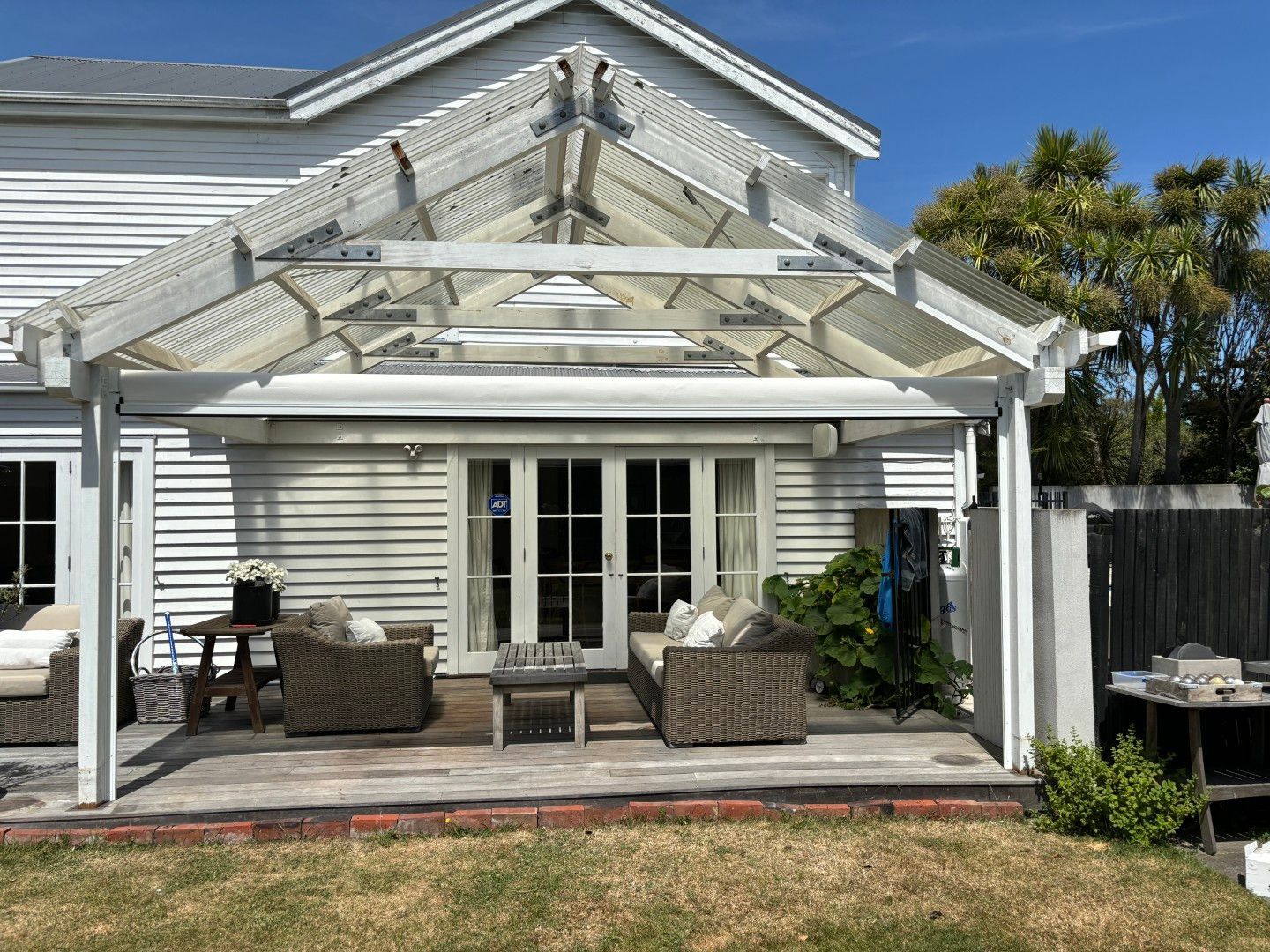 A white house with a patio area and a pergola in the backyard.