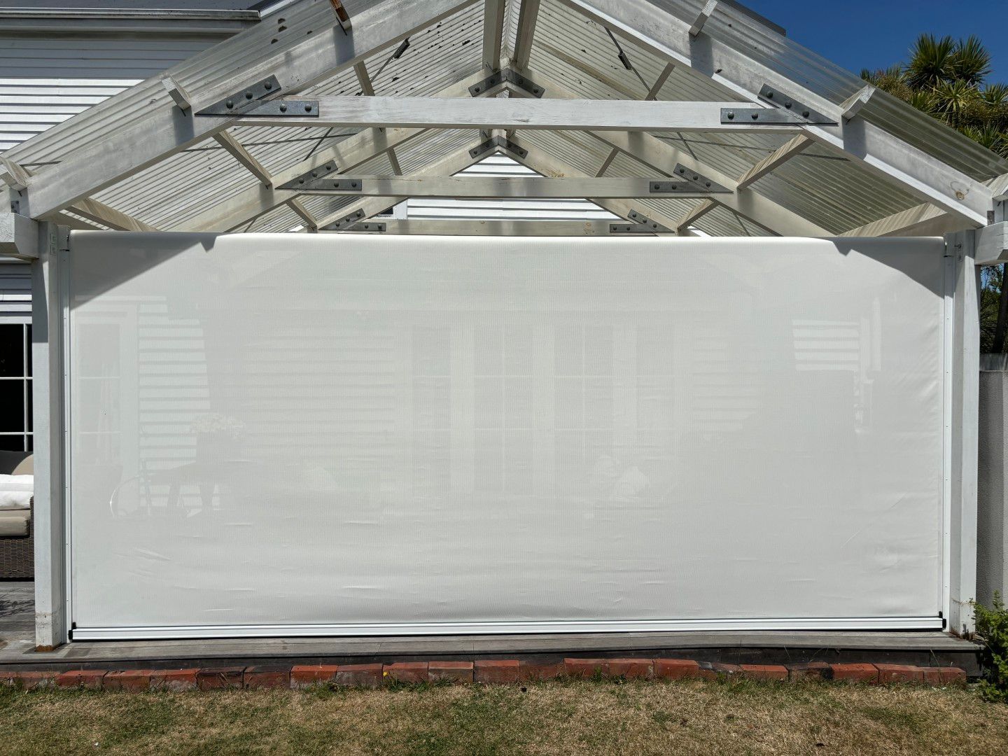 A white screen is hanging on the side of a house.