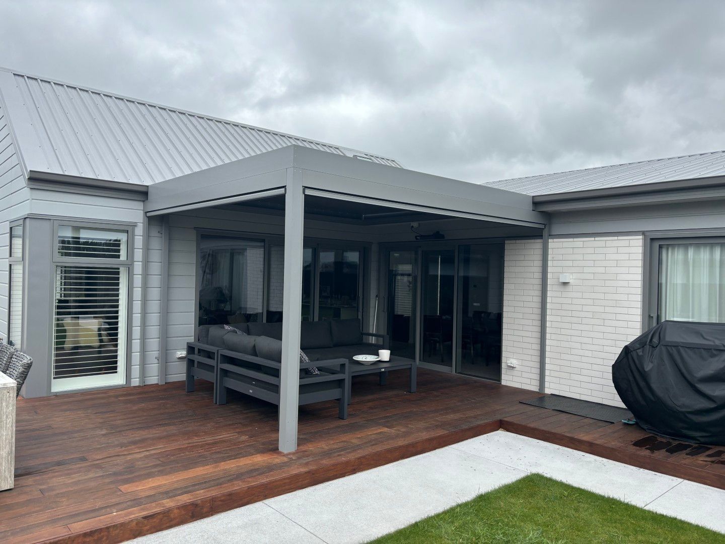 A house with a wooden deck and a pergola in the backyard.