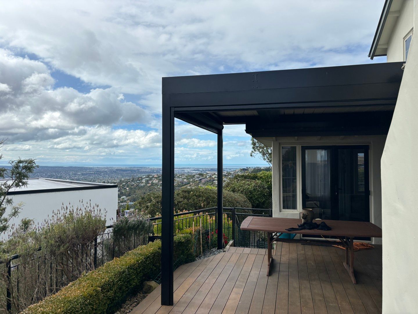 There is a table on the deck of a house with a view of the ocean.