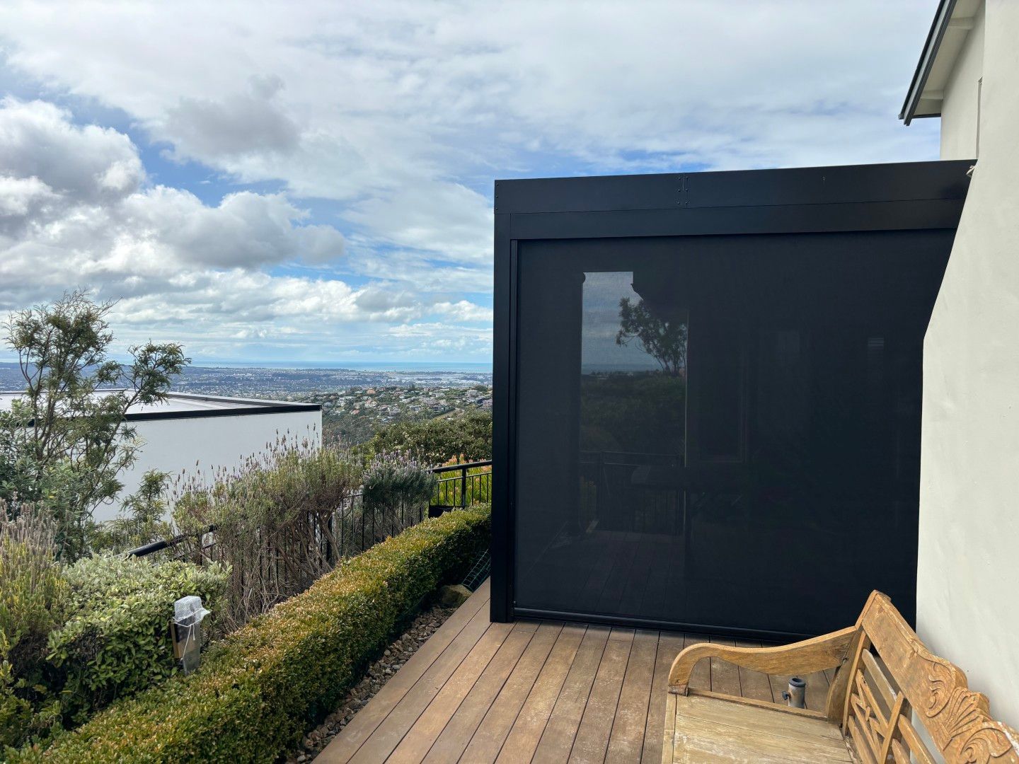 A wooden deck with a bench and a black building in the background.