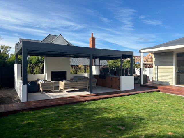 A backyard with a large covered patio area and a house in the background.