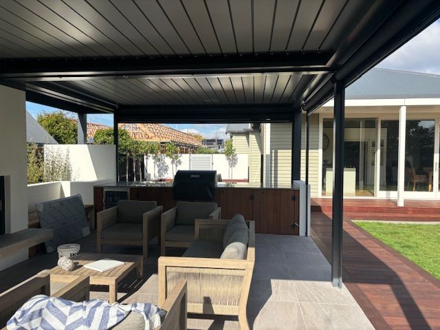 A living room with a couch and chairs under a pergola