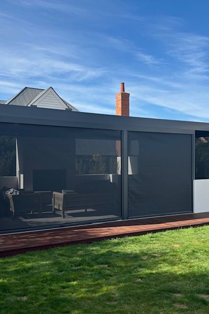 A house with a lot of windows and a lot of grass in front of it.