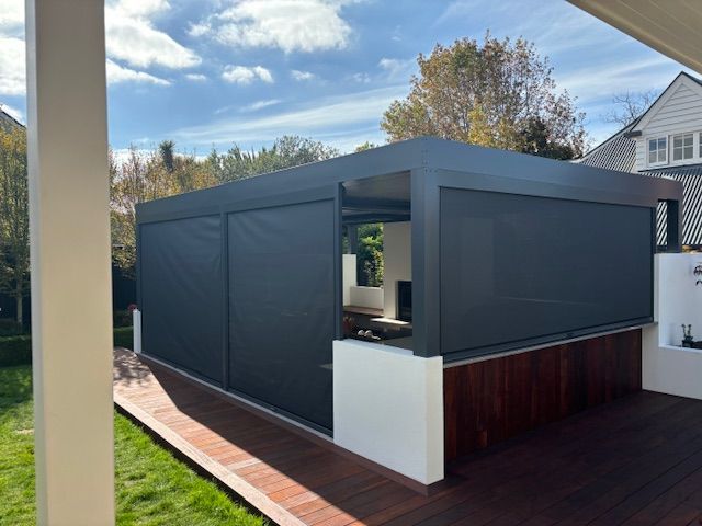 A large black building with a wooden deck in front of a house.