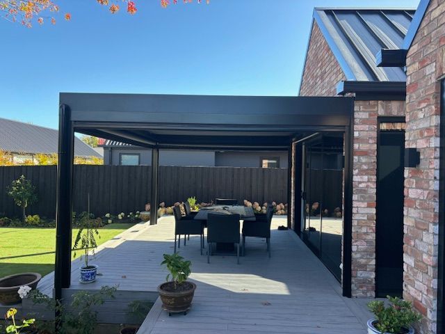 A patio with a table and chairs under a pergola.