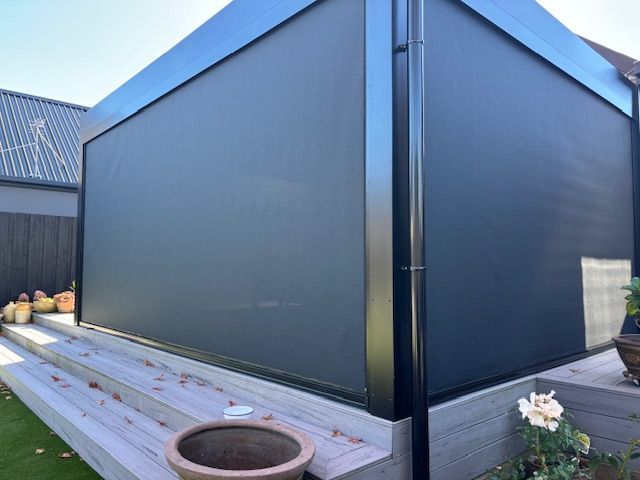 A potted plant is sitting on a wooden bench in front of a building.