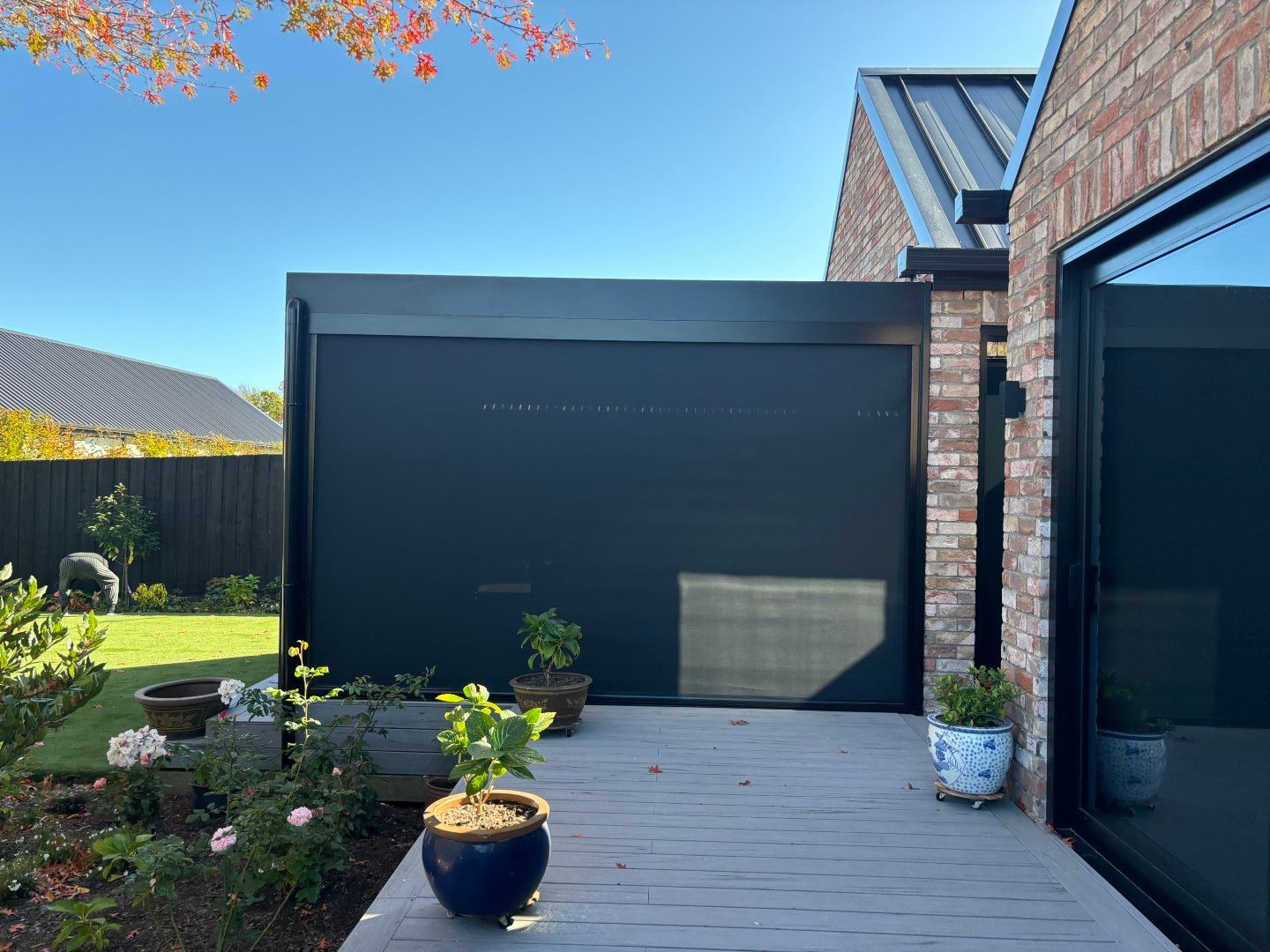 A brick house with a black garage door and a patio with potted plants.