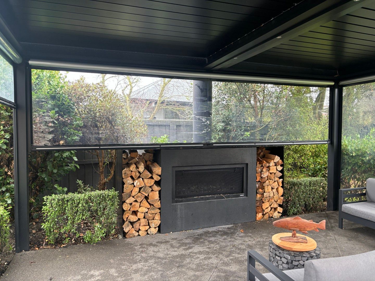 A patio with a fireplace and a stack of logs.