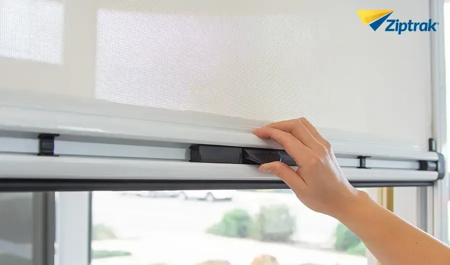 A person is adjusting a mosquito screen on a window.
