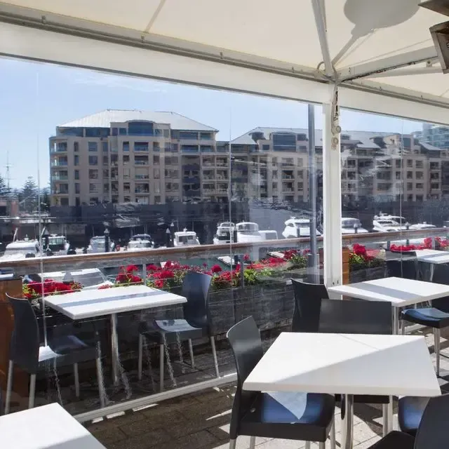 A restaurant with tables and chairs and a view of boats