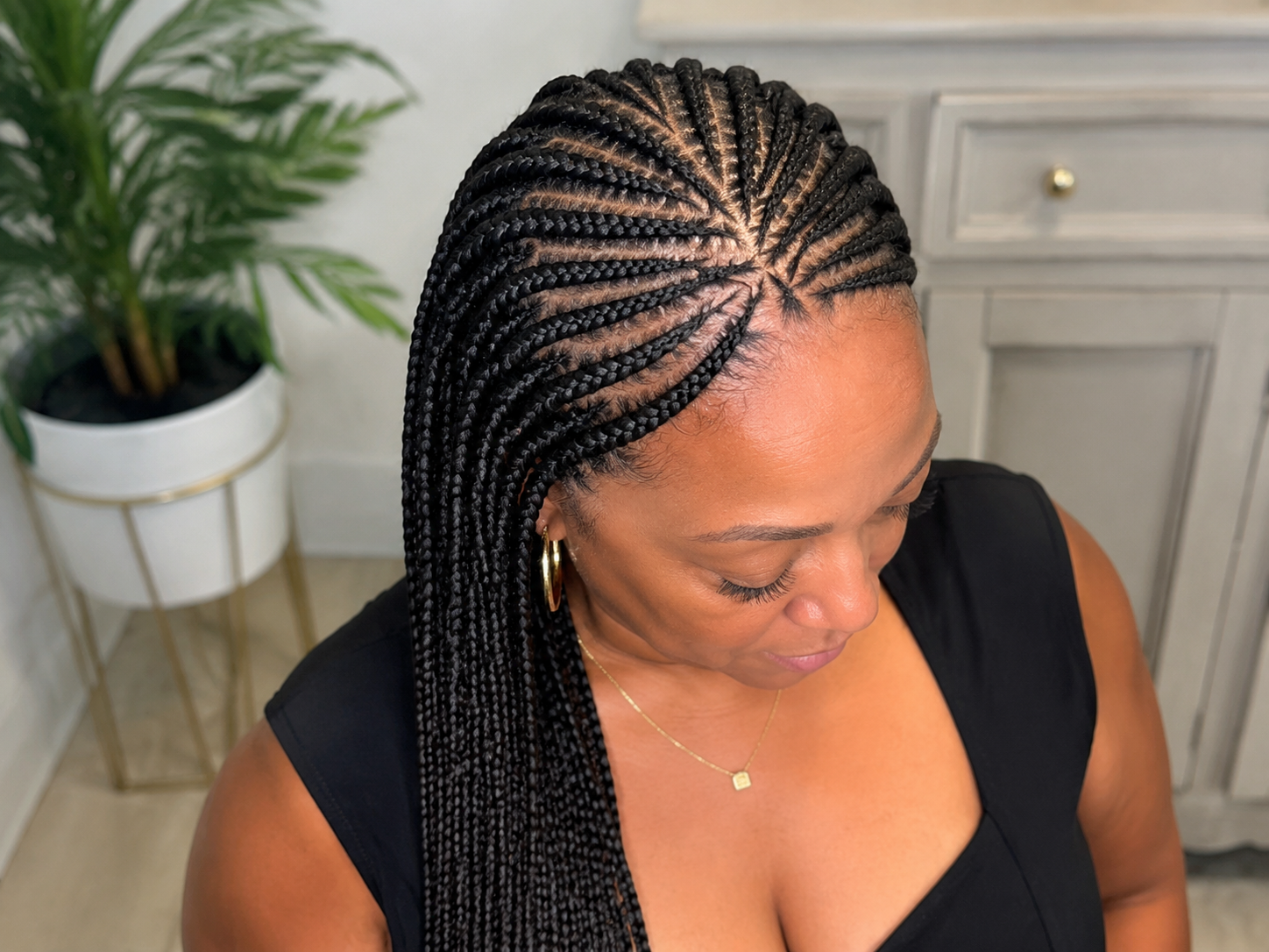 Hands braiding hair using a comb; close-up of hair in a salon.