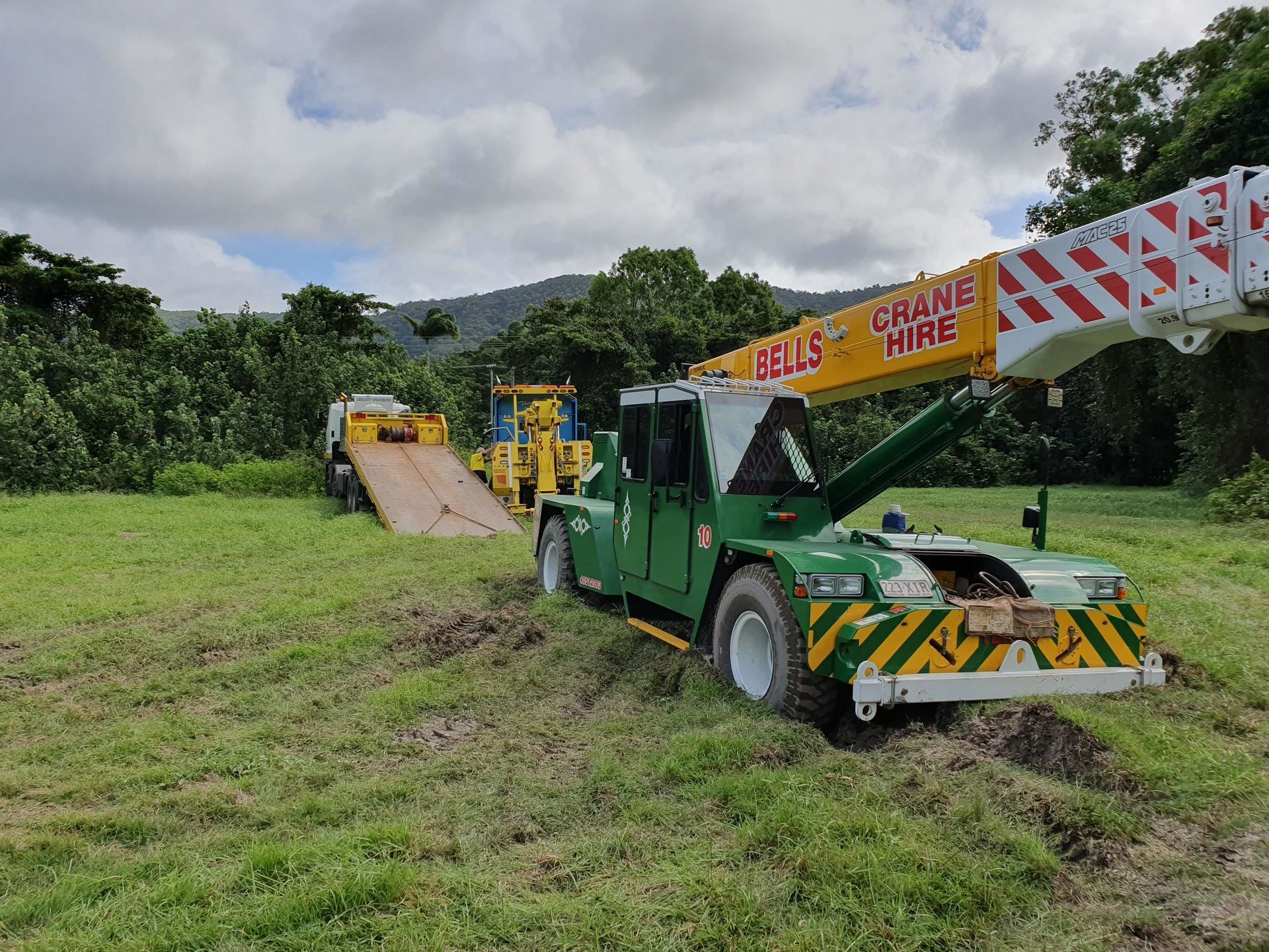 A Green Crane Stuck in Muddy Grass — Bell's Carrying & Crane Hire Service Pty Ltd in Bungalow, QLD
