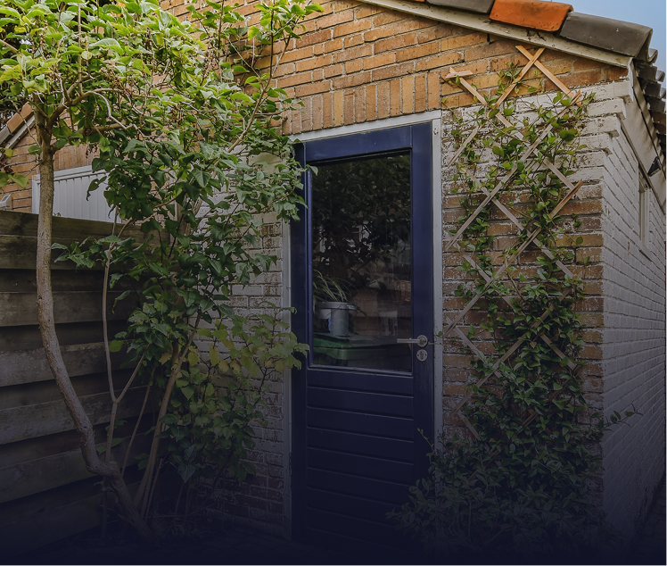 Small brick shed with a blue door. Green climbing plants frame the entrance.