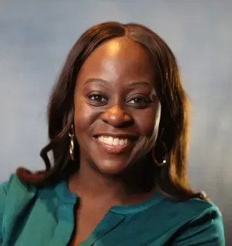 A woman in a green shirt is smiling for the camera.